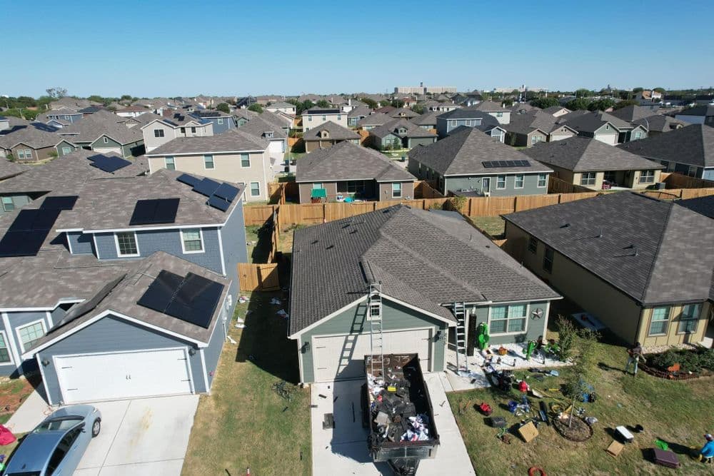 Aerial view of residential neighborhood with houses, solar panels, and a construction site.