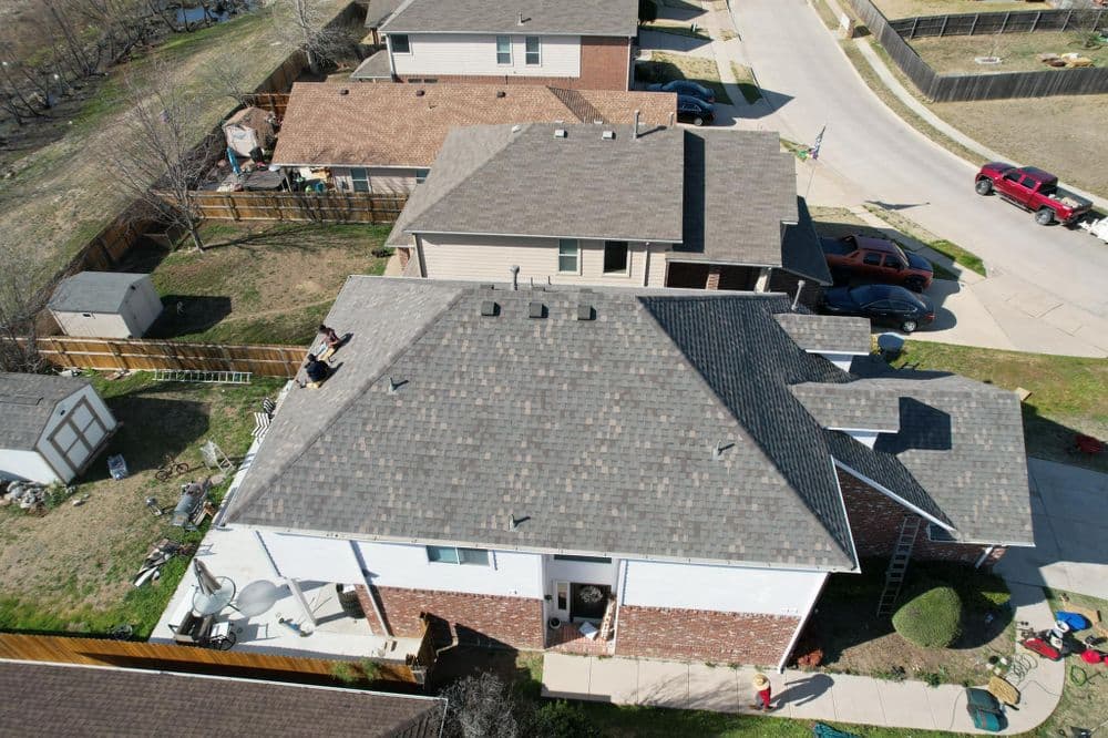 Aerial view of suburban homes with various roof types and yard features.