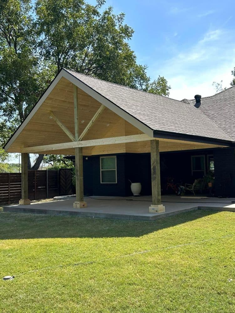 Modern patio cover design with wooden beams and a spacious concrete area in a backyard.