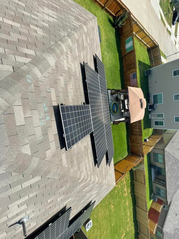 Solar panels installed on a residential roof overlooking a backyard and patio area.