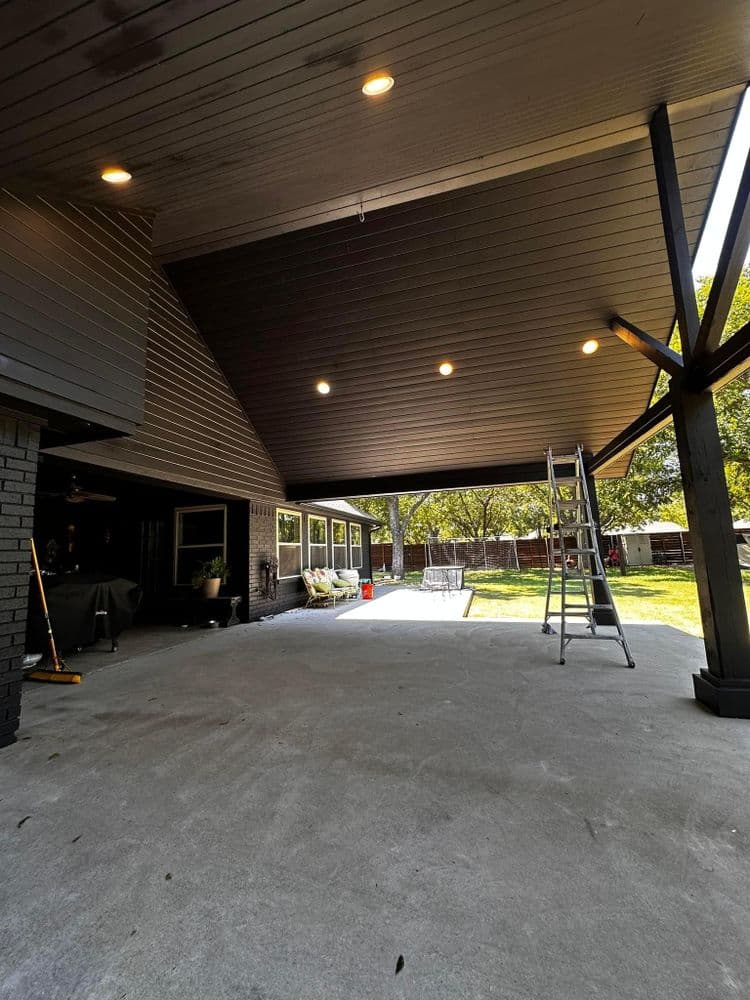 Spacious covered patio with modern lighting and a ladder, ideal for outdoor gatherings.