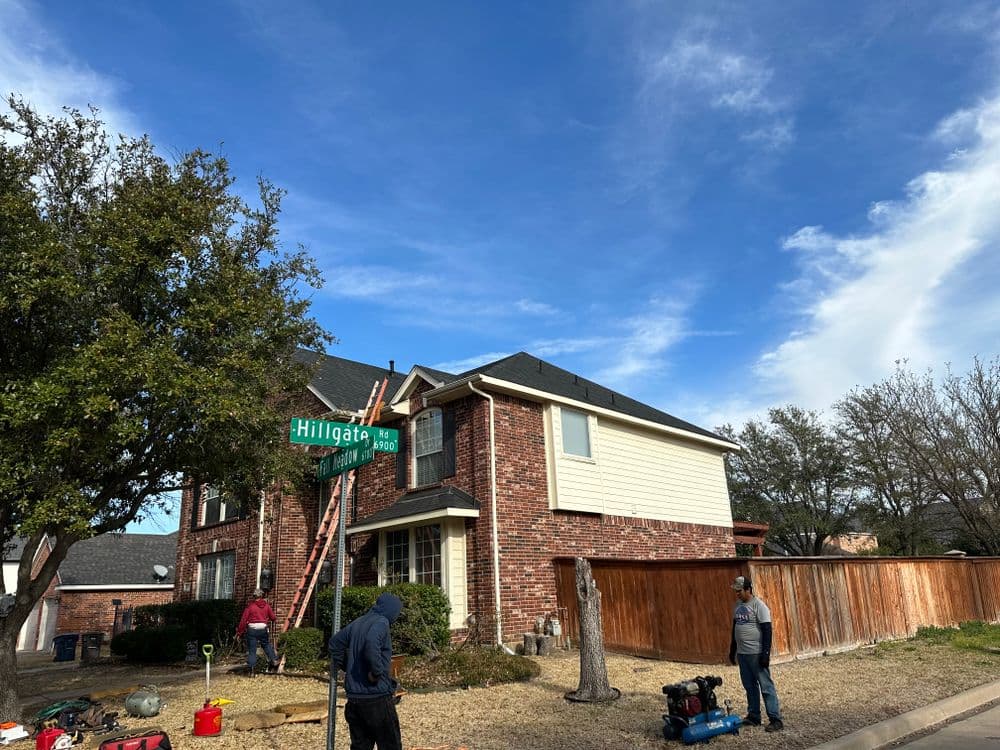 Workers installing equipment on a house under a clear blue sky on Hillgate Street.