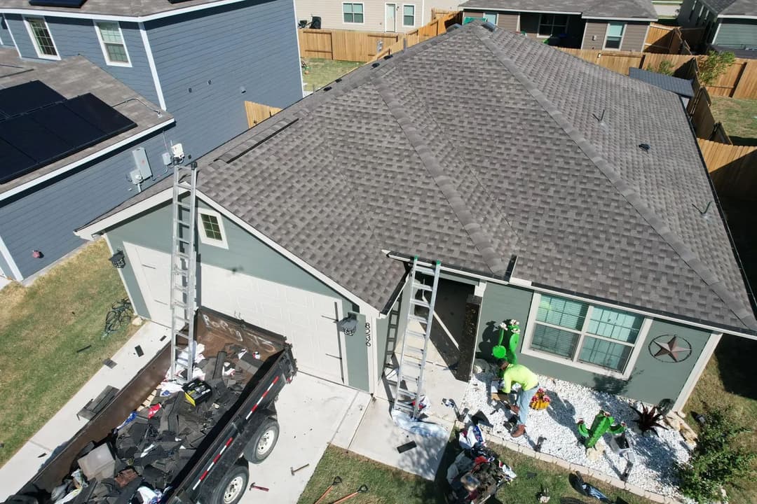 Rooftop inspection and maintenance on a residential home with ladders and equipment visible.