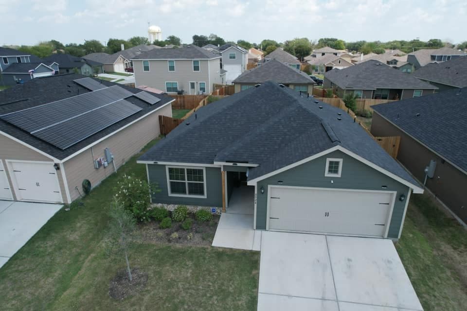 Aerial view of a modern gray house with a landscaped yard in a suburban neighborhood.