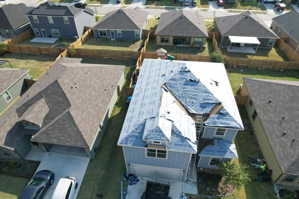 Aerial view of residential homes with a roof under renovation near construction equipment.