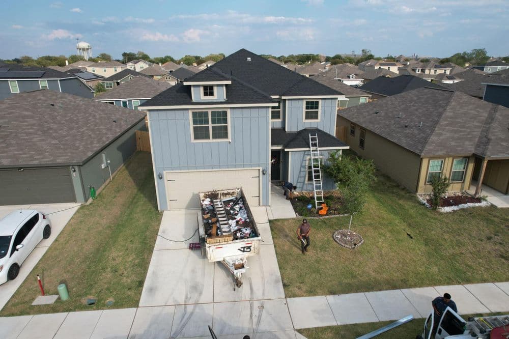 Two-story house with a ladder, renovation supplies outside, near residential area.