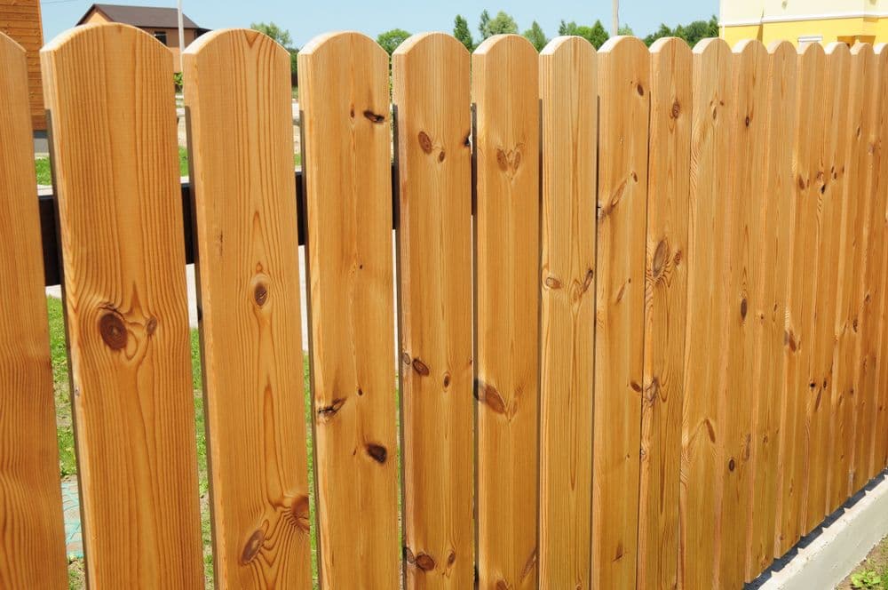 Wooden fence panels in a sunny outdoor setting with green grass in the background.