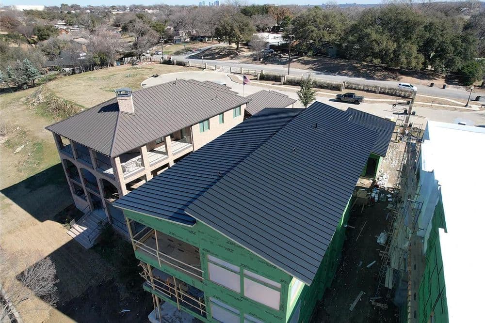 Aerial view of two buildings with new black metal roofs in a suburban area.