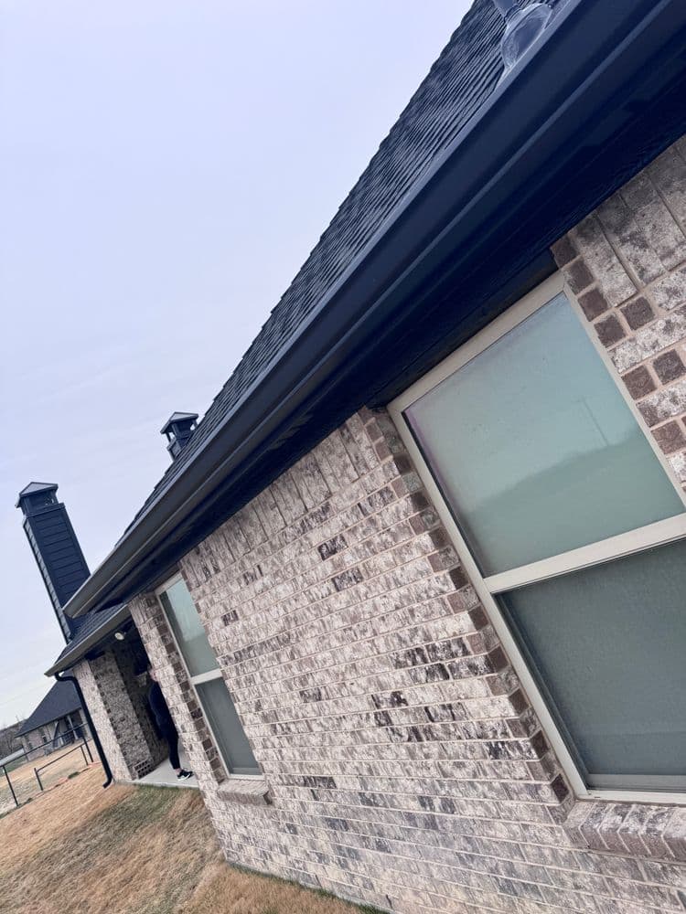 Exterior view of a modern brick home with a sloped roof and large windows.