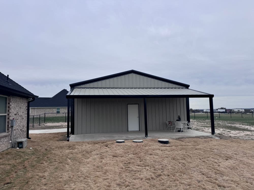 Modern metal building with a gray exterior and porch in an open landscape.