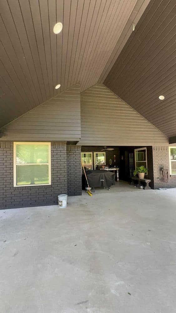 Modern home entrance with a covered porch, large windows, and dark brick exterior.