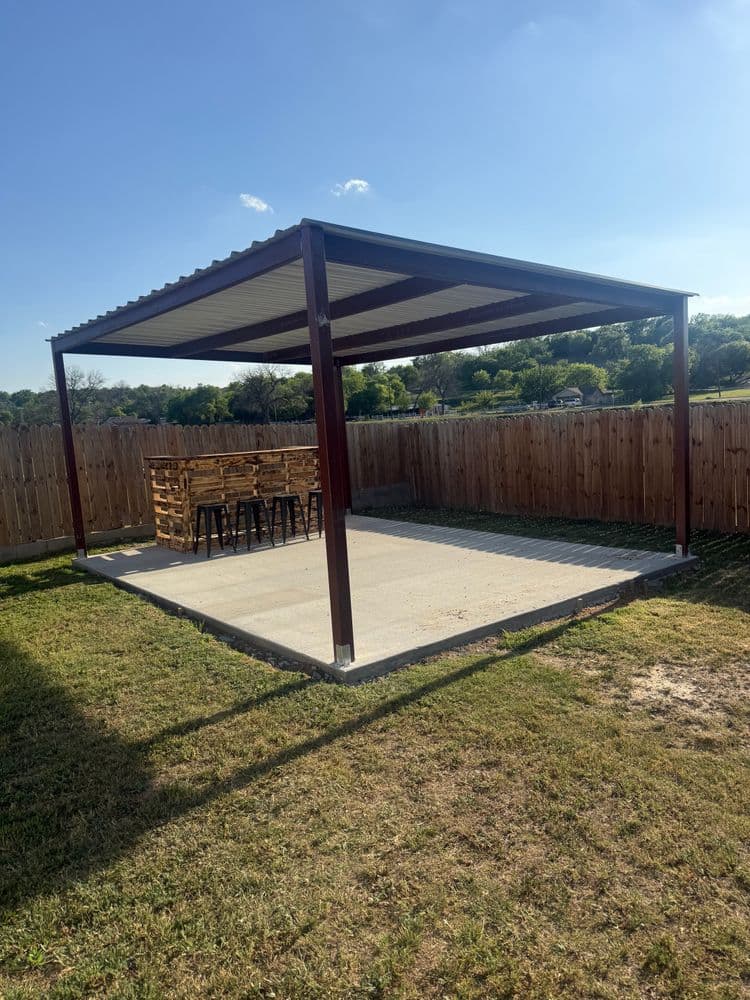Modern outdoor patio shelter with a bar setup and fenced yard, perfect for gatherings.